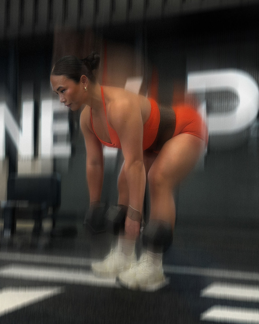 woman doing deadlift variations wearing uppper lifting straps