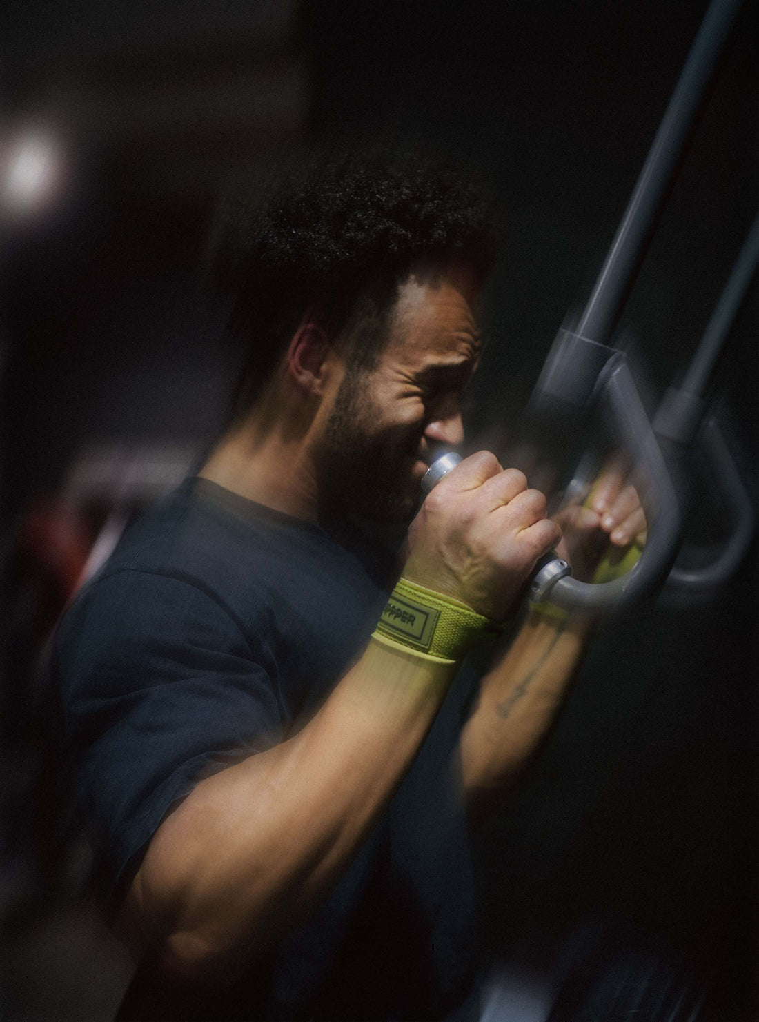 man using upper body gym machine using uppper lifting straps