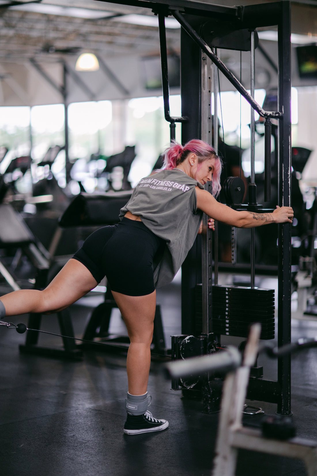 woman doing cable leg workout with uppper ankle straps